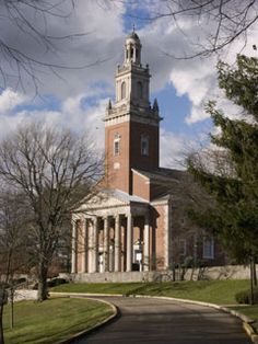 an old brick building with a clock tower in the middle of it's front yard