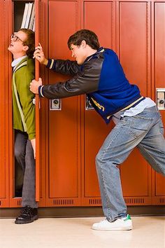 two young men standing in front of lockers with their hands on the door handles