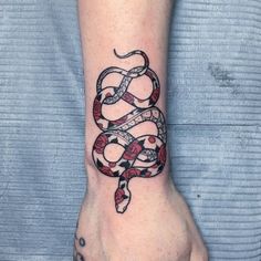 a snake tattoo on the wrist is shown in black and red colors, with an intricate design