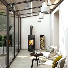 a room with a chair, table and fire place in it that has glass walls