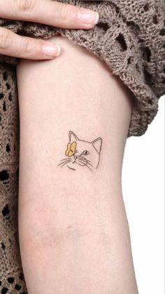 a small cat tattoo on the left side of the arm, with a yellow flower in it's ear