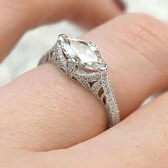 a woman's hand holding an engagement ring with a large white diamond in the center