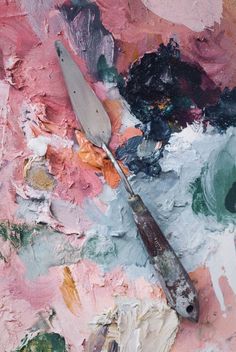 an artist's palette and paintbrush sitting on top of a piece of art