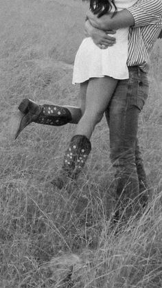 black and white photograph of a man hugging a woman in a field with tall grass