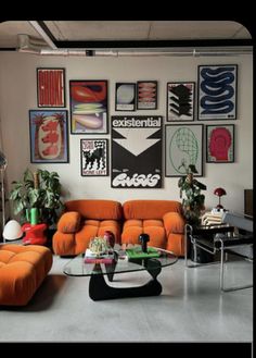 a living room filled with orange couches and pictures on the wall above them,