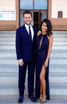 a man and woman in formal wear posing for a photo on the steps of a building