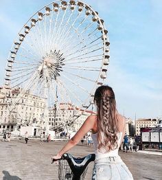 a woman riding a bike in front of a ferris wheel with her hair pulled back