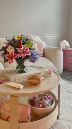 a coffee table with flowers in a vase on it and other items around the table