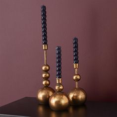 three gold and black candlesticks sitting on top of a table next to each other