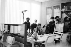 a group of people standing around a table in front of a tv camera and recording equipment