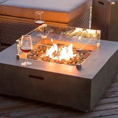 a fire pit sitting on top of a wooden table next to a glass of wine