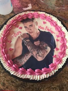 a birthday cake with a photo of a tattooed man on the side and pink icing