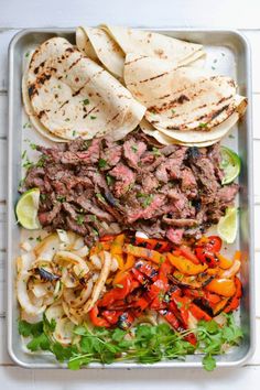 a tray filled with tacos, tortillas and meat