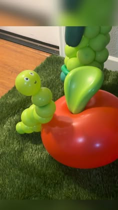 an inflatable caterpillar sitting on top of a red ball laying on the ground