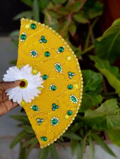 a person holding a yellow and white flower in their left hand with an umbrella made out of sequins