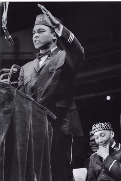 a black and white photo of a man standing at a podium with his hands up