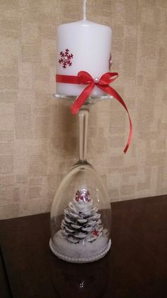 a glass candle holder with a christmas tree inside and a red ribbon on the top