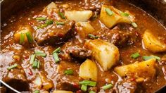 a pot filled with stew and potatoes on top of a table