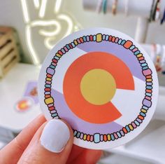 a person holding up a sticker with the letter q in it's center