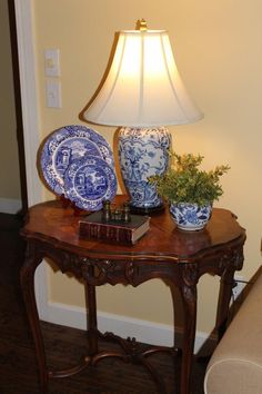 a blue and white vase sitting on top of a wooden table next to a lamp