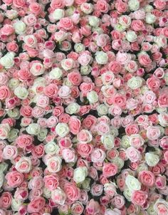 many pink and white flowers are arranged in the shape of a flower arrangement on a wall