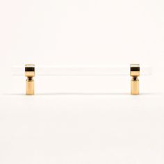 two gold - plated objects are sitting on a white surface