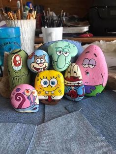 some rocks with cartoon characters painted on them sitting on a table next to pens and pencils