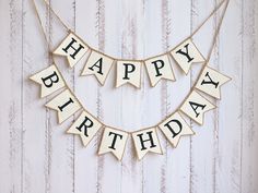 a happy birthday banner hanging from a string on a white wooden wall with the words happy birthday spelled out