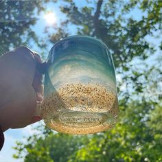 a person is holding a mason jar filled with bird seed and drinking water from it