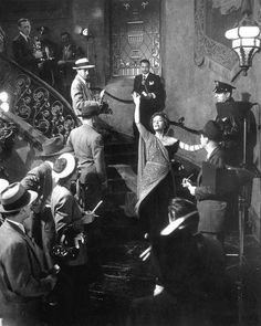 an old black and white photo of people on the stairs with their hands in the air