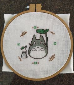 a cross stitch pattern with a totoro holding a plant