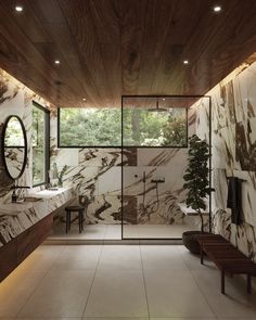 a bathroom with marble walls and flooring next to a wooden bench in front of a window