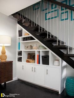 a white bookcase under a stair case next to a lamp