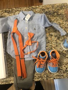 a blue shirt and orange tie sitting on top of a counter next to shoes, water bottle