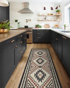 a kitchen with wooden floors and black cabinets, an area rug on the floor that matches the cabinetry