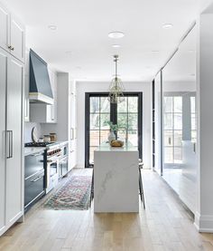 a kitchen with white cabinets and an island in front of a stove top oven next to a doorway