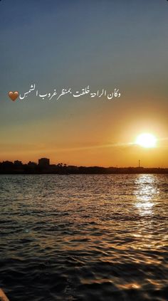 the sun is setting over some water with words written in english and arabic on it