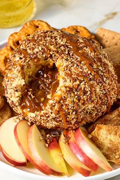 a bagel filled with nuts and apple slices on a plate next to crackers