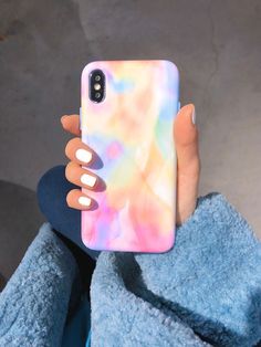 a woman's hand holding up a phone case that is covered in multicolored liquid