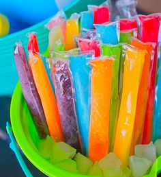 there are many popsicles in the green bowl on the table and one is filled with them