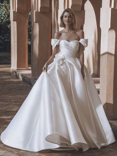 a woman in a white wedding dress posing for the camera with her hand on her hip