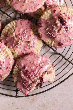 cookies with pink icing and sprinkles on a wire rack