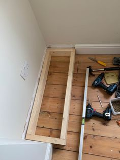 tools are laying on the floor next to an unfinished piece of wood that has been framed