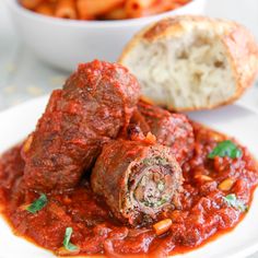 a white plate topped with meatballs covered in marinara sauce next to some pasta