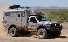 a truck driving down a dirt road in the desert