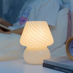 a white lamp sitting on top of a table next to a book and a clock