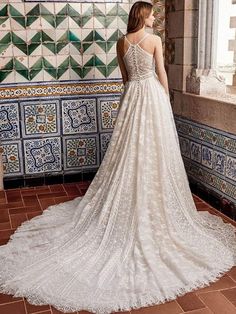 a woman standing in front of a tiled wall wearing a wedding dress with an open back