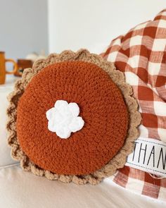 a close up of a crocheted pillow on a bed with a name tag