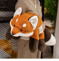 a person holding a stuffed animal that looks like a fox