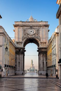 an arch with a clock on it in the middle of a street